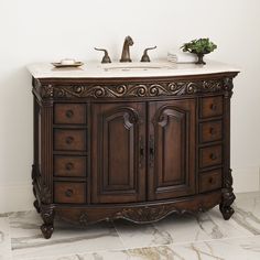 a bathroom vanity with marble top and carved wood design on the cabinet door, along with two faucets