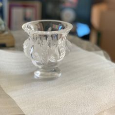 a clear glass vase sitting on top of a white table cloth covered table with a book