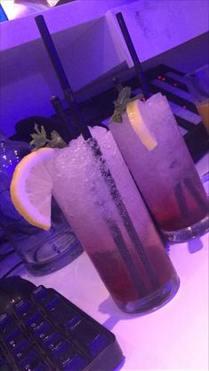 two glasses filled with drinks sitting on top of a table next to a keyboard and mouse