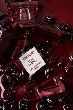 a bottle of tom ford lost cherry jam on top of jelly candies in a bowl