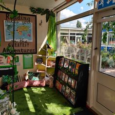 a room filled with lots of green plants and pictures on the wall next to a window