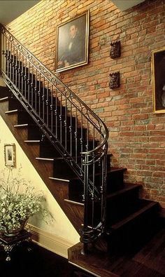 there is a stair case next to a brick wall and potted plants on the floor