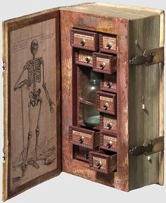 an open wooden box with drawers and skeleton artwork on the inside, in front of a white background