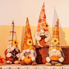 three gnomes are sitting on a shelf with pumpkins and sunflowers in their hats