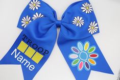 a blue ribbon with flowers on it and the word troop painted on it is laying on a white surface