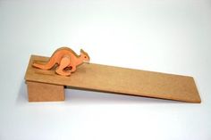 a wooden toy kangaroo sitting on top of a piece of wood with a ruler in front of it