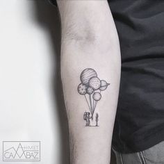 a man with a tattoo on his arm holding onto a balloon that is floating in the air