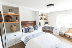 a bed sitting in a bedroom next to a white dresser and window with lots of shelves