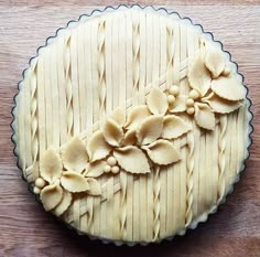 an uncooked pie with white frosting and flowers on the top is sitting on a wooden table