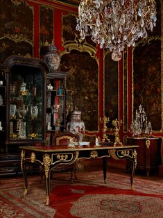 an ornately decorated room with red walls and gold trimmings, including a chandelier