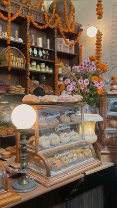 an assortment of pastries on display in a bakery shop with flowers and garlands hanging from the ceiling