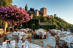 an outdoor dining area with many tables and chairs set up for formal function in front of a castle