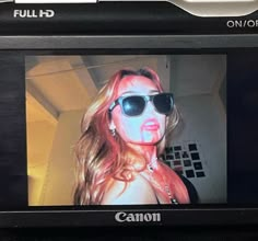 a digital camera with a woman wearing sunglasses on it's face and the screen showing an image of herself