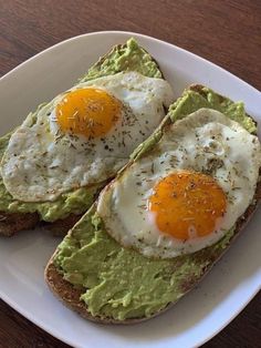 two fried eggs are on top of avocado toast