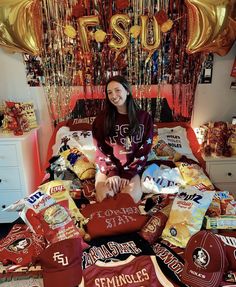 a young woman sitting on top of a bed covered in lots of food and balloons