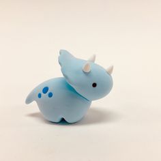 a small blue toy animal with horns on it's head and tail, sitting in front of a white background