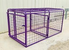 a purple dog cage sitting on top of a cement floor in front of a building