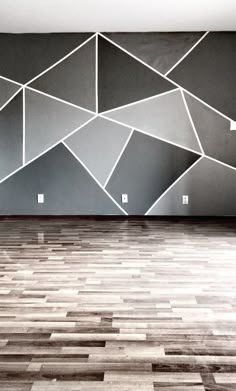 an empty room with wood flooring and large wall art on the walls behind it