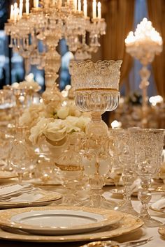 Elegant table setting with intricate glassware, white roses, and gold accents under ornate chandeliers. Everyday Dining Table Decor, Simple Centerpiece Ideas, Simple Centerpiece