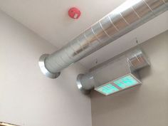 two metal pipes are attached to the ceiling in a room with white walls and flooring