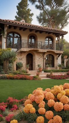 a large house with many windows and flowers in the front yard