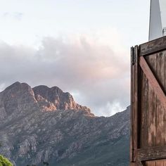 the mountains are covered in clouds and there is a wooden door open to reveal it