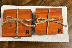 two wooden blocks tied with twine on top of each other and the letters r and m are made out of wood