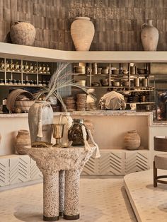 a room filled with vases and other items on top of a table in front of shelves