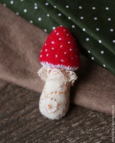 a small red and white mushroom sitting on top of a green blanket next to a pillow