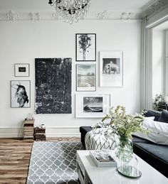 a living room filled with furniture and pictures hanging on the wall above a coffee table