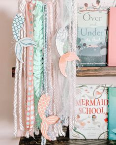 a shelf with books and paper garlands hanging from it