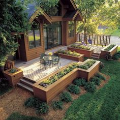 a wooden deck with raised planters on it and an outside dining area in the background