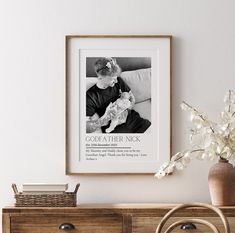 a black and white photo hanging on the wall next to a wooden dresser with a vase filled with flowers