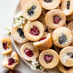 a plate full of small pastries with berries on them next to some other desserts