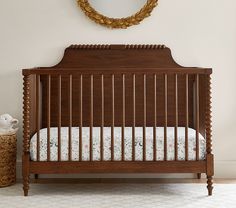 a baby crib in front of a wall with a mirror on the wall above it