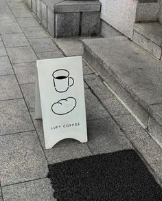 a sign that is sitting on the ground next to some steps and coffee cup in front of it