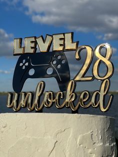 a cake topper that says level 28 unlocked with a video game controller on it