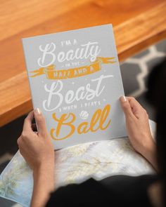 a person holding up a book that says i'm a beauty and beast ball