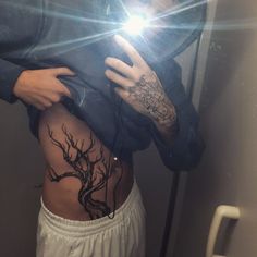 a person with tattoos on their stomach holding a cell phone