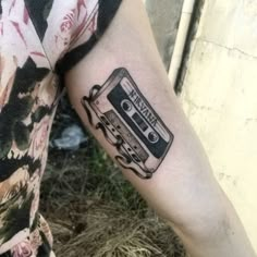 a person with a tattoo on their arm has a cassette in the shape of a car