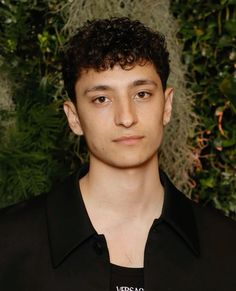 a young man with curly hair wearing a black shirt