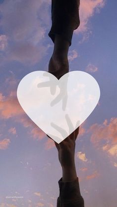 a person holding up a white heart in the sky