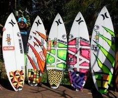 a man standing next to five surf boards