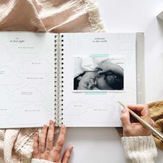 a person holding a pen and looking at an open book on a table with pictures