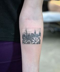 a black and white photo of a cityscape tattoo on the left arm, with buildings in the background