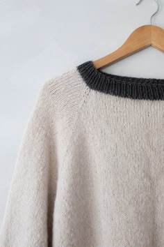 a white sweater hanging on a wooden hanger