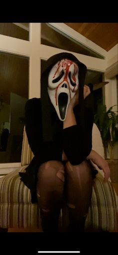 a woman wearing a mask sitting on top of a couch