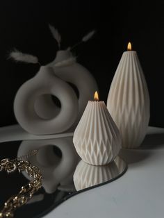 two white vases sitting on top of a table next to a necklace and bracelet