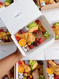 several boxes filled with assorted fruits and pastries next to someone's hand