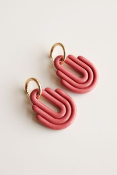 two pink earrings with gold rings on them